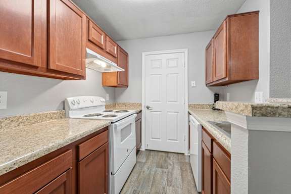 A kitchen with white appliances and wooden cabinets.